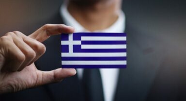 a businessman holding a card with the national flag of Greece on it