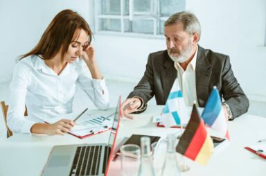 Two professionals discussing over documents with flags on table